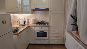 Une cuisine compacte avec des meubles blancs, un four encastré, une cuisinière à gaz et un réfrigérateur.