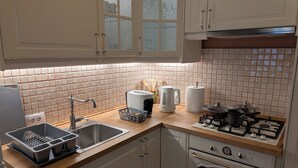 Une cuisine équipée d’un évier, d’un grille-pain, d’une bouilloire, d’une casserole et d’une cuisinière.