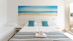 Een hotelkamer met een bed, twee nachtkastjes, een telefoon en een schilderij van een strand.