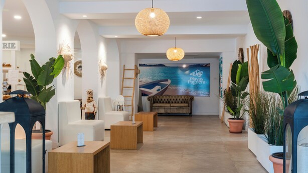A reception area with a seating arrangement, a large poster, and potted plants. - Hotel Playas de Paguera (Calvia)