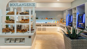 Een bakkerijafdeling met een bord waarop 'BOULANGERIE' staat en diverse gebakken producten op planken.