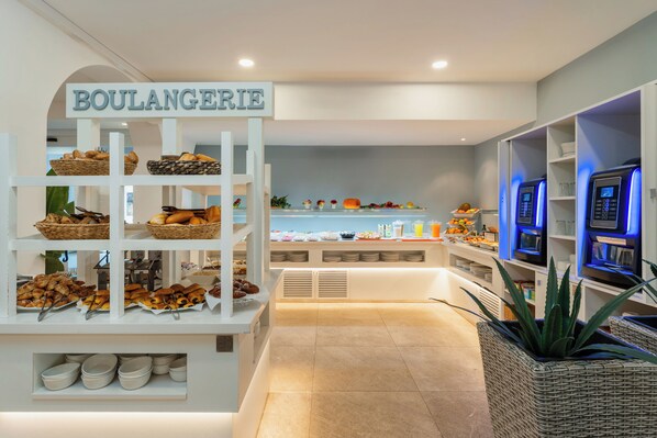 Un rayon boulangerie avec une enseigne indiquant « BOULANGERIE » et diverses pâtisseries et pains exposés sur des étagères.