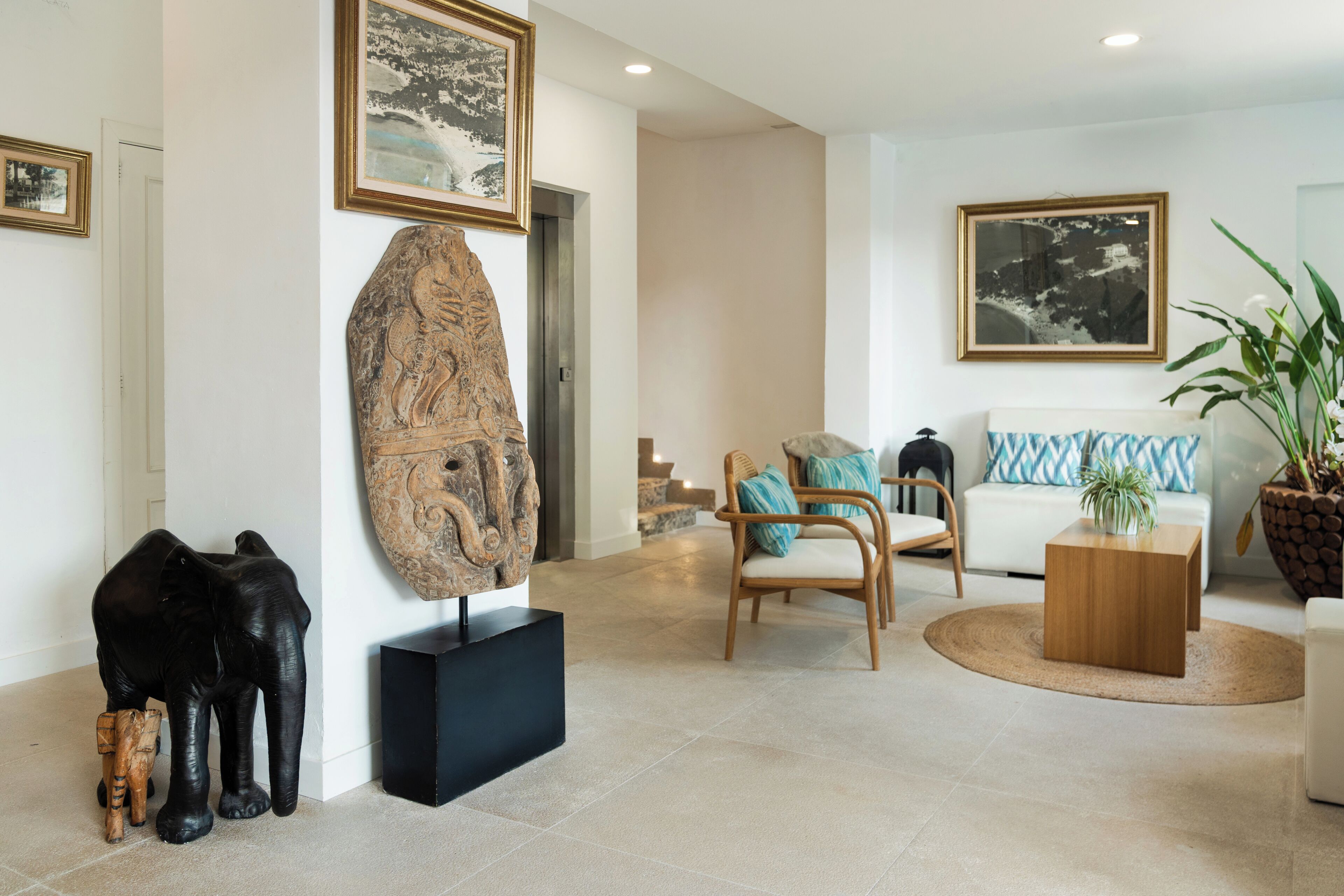 A modern living room with a sofa, chairs, a coffee table, and a large sculpture.