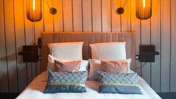 Una habitación de hotel con una cama, dos lámparas de pared y un panel de pared de madera.
