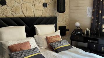 A bedroom with a stone wall, a black headboard, and a bed with multiple pillows.