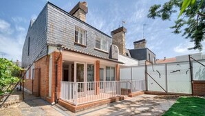 Une maison à deux étages avec une façade en briques, un balcon et une cour arrière clôturée.