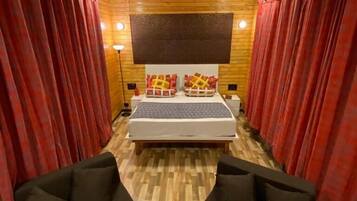 A hotel room with a bed, two black sofas, a small white table, and a ceiling light.