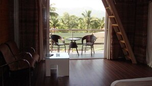 A room with a balcony, a table with chairs, a bed, and a ladder. - Rumourss Sky Villa (Lonavala)