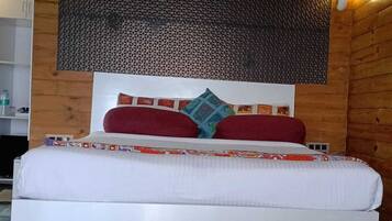 A bed with white bedding, red and blue pillows, and a patterned headboard.