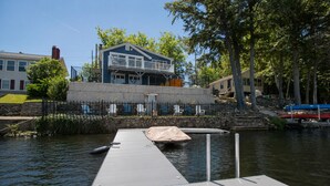 A dock extending into a calm body of water with a house in the background. - Lakefront Home w/ Private Dock & Water Access (Shapleigh)