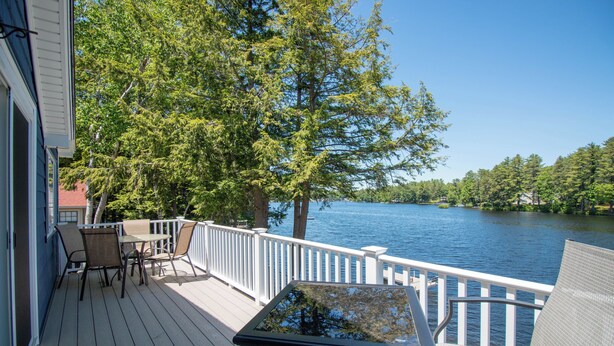 A deck with outdoor furniture, a glass table, and a view of a lake. - Lakefront Home w/ Private Dock & Water Access (Shapleigh)