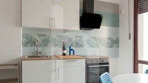 A kitchen with a stove, oven, sink, and a blue chair. - Welcome to Homiday Yellow Submarine, a modern, fully renovated apartment just a 10-minute walk from the Viareggio seafront. Bright and welcoming, it features a double bedroom, a comfortable sofa bed, a fully equipped kitchen, air conditioning, a washing  (Viareggio)