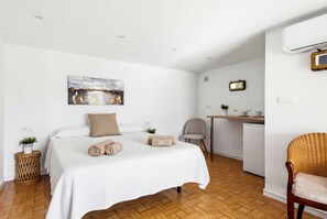 A bedroom with a bed, a desk, a chair, a small table with cups, and a painting on the wall. - Villa Varadero by Escape Home (Alaior)