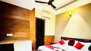 Ein Schlafzimmer mit Holzboden, einem Bett mit rot-weißer Bettwäsche, einem Deckenventilator und einer Klimaanlage.