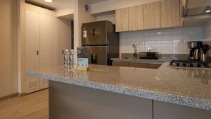 Une cuisine moderne dotée de plans de travail en granit, d’appareils électroménagers en acier inoxydable et d’armoires en bois.
