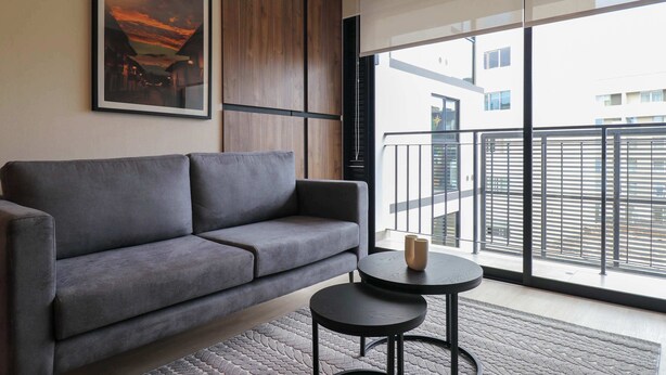 Un salon moderne avec un canapé gris, une petite table ronde et un tableau encadré accroché au mur.