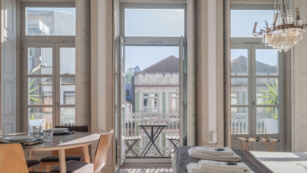 A hotel room with a balcony, a dining area, and a bed with towels. - Liiiving in Porto - Design Palace Studio (Porto)