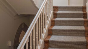 A staircase with white balusters and wooden steps, leading to a landing with a framed artwork and a fireplace. - Liiiving in Porto - Design Palace Studio (Porto)