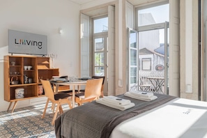 Une chambre d’hôtel comprenant un lit, une télévision, une armoire en bois, une table à manger, des chaises et un balcon avec vue.