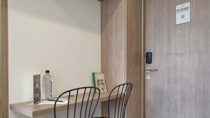 A small room with a wooden desk, two black chairs, a bottle, a book, and a door with a 'BYE FOR NOW!' sign. - w Wonderful Loft in the Heart of Bogot (Bogotá)