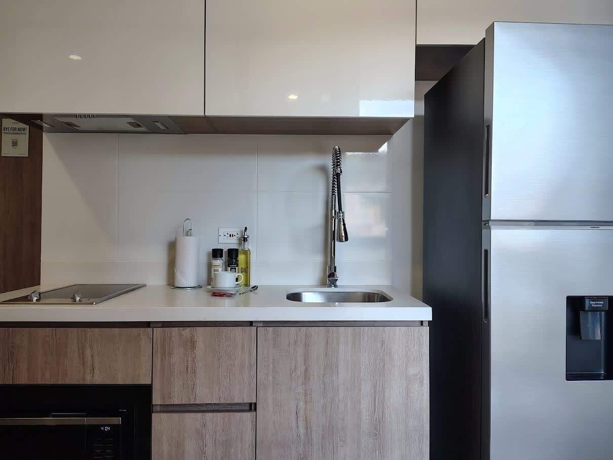 A modern kitchen with a stainless steel refrigerator, a sink, and wooden cabinets.