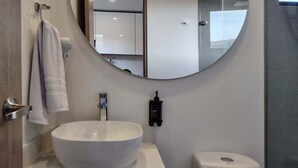 Une salle de bain moderne avec un lavabo blanc, des toilettes et un grand miroir.