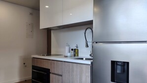 Une cuisine moderne dotée d’un réfrigérateur en acier inoxydable, de meubles en bois, d’un four encastré et d’un évier avec un robinet.