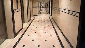 A long, narrow hotel corridor with marble flooring and patterned walls. - Grand Jawaher Alhashmiye Hotel Makkah (Makkah)