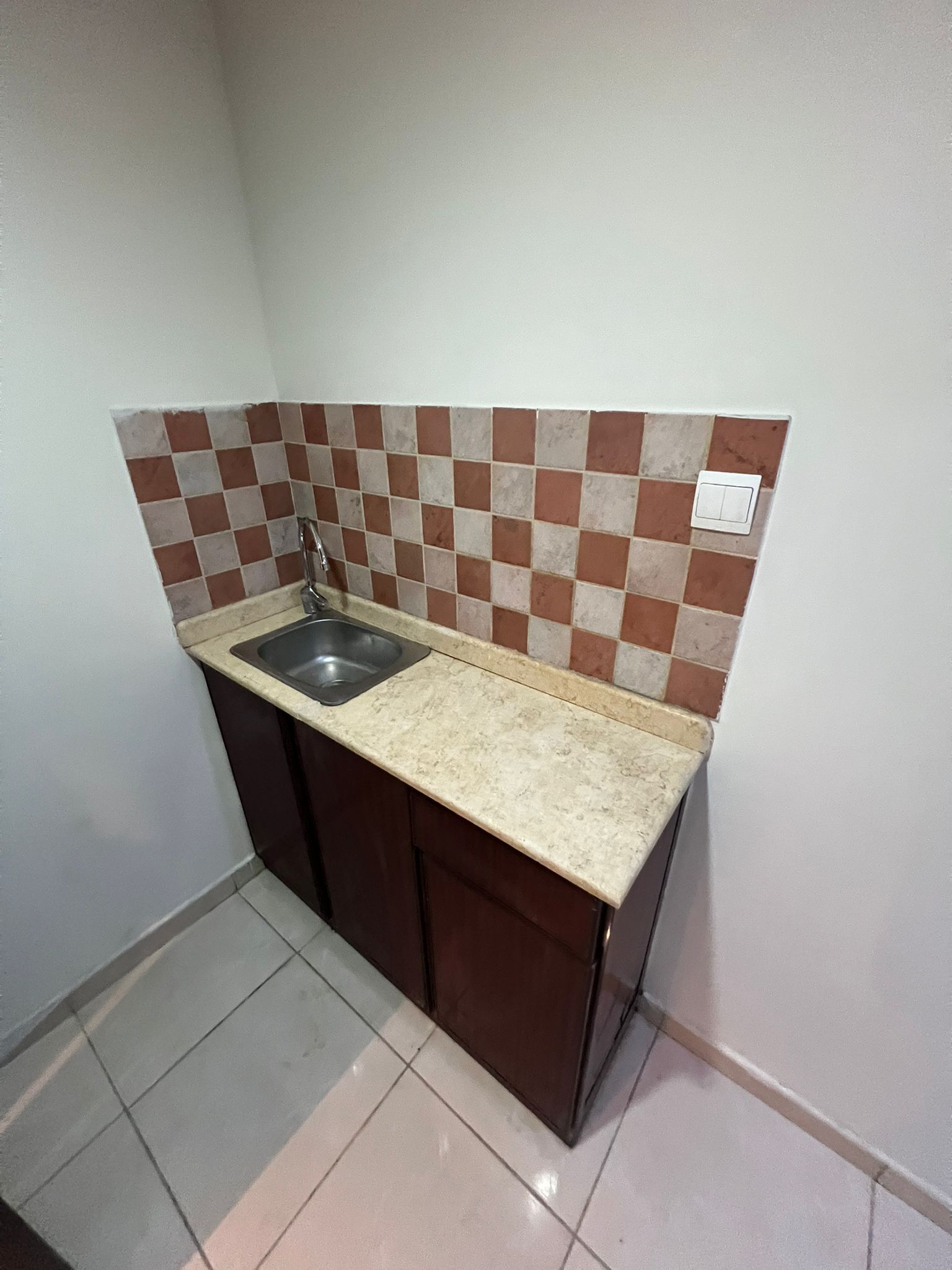 A small kitchen with a sink, a countertop, and a tiled backsplash.