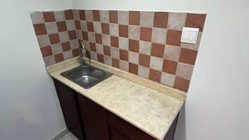 A small kitchen with a sink, a countertop, and a tiled backsplash.