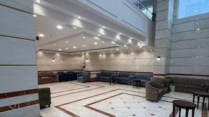 A spacious lobby with a high ceiling, marble flooring, and a seating area with sofas and chairs. - Grand Jawaher Alhashmiye Hotel Makkah (Makkah)