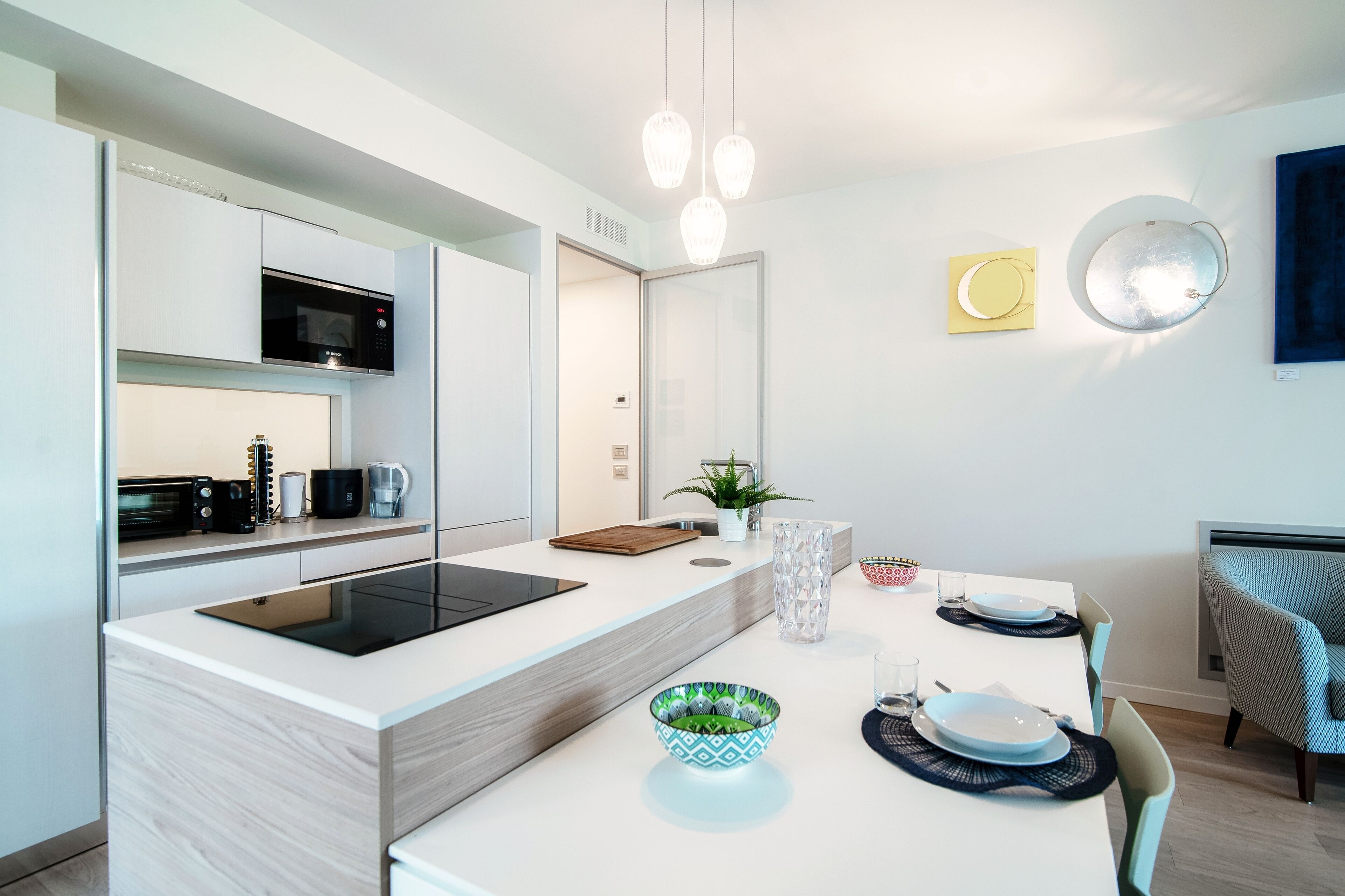 A modern kitchen with a central island, built-in microwave, and a dining area with a table set for four.