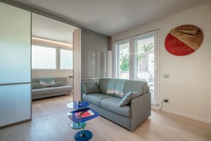 A modern living room with a grey sofa, a striped couch, and a small blue table with a book and a pen. - The Art House (Cernobbio)