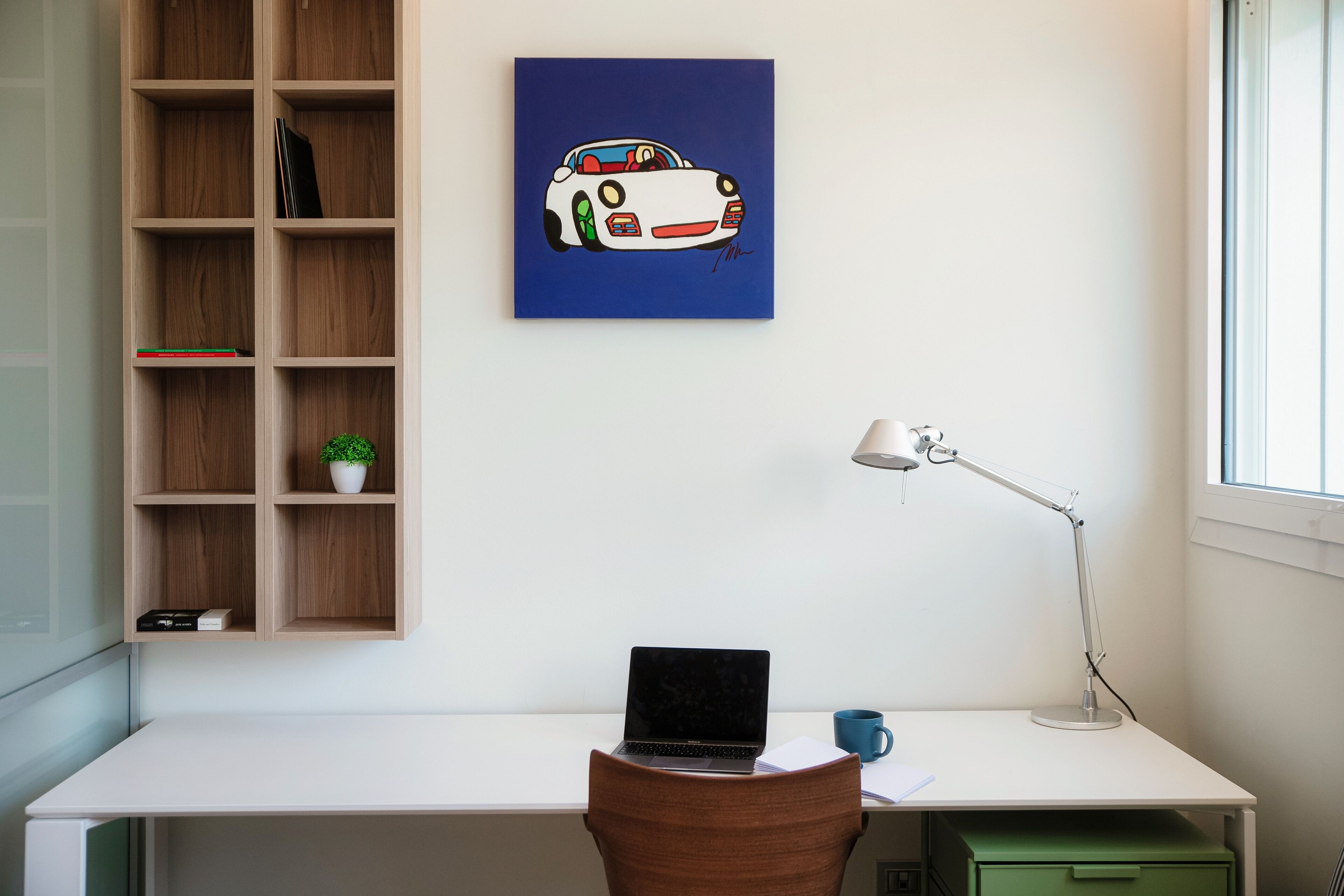 A workspace with a desk, laptop, and a blue mug.