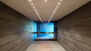 Un pasillo moderno con suelo y paredes de madera que conduce a una habitación azul con un banco.