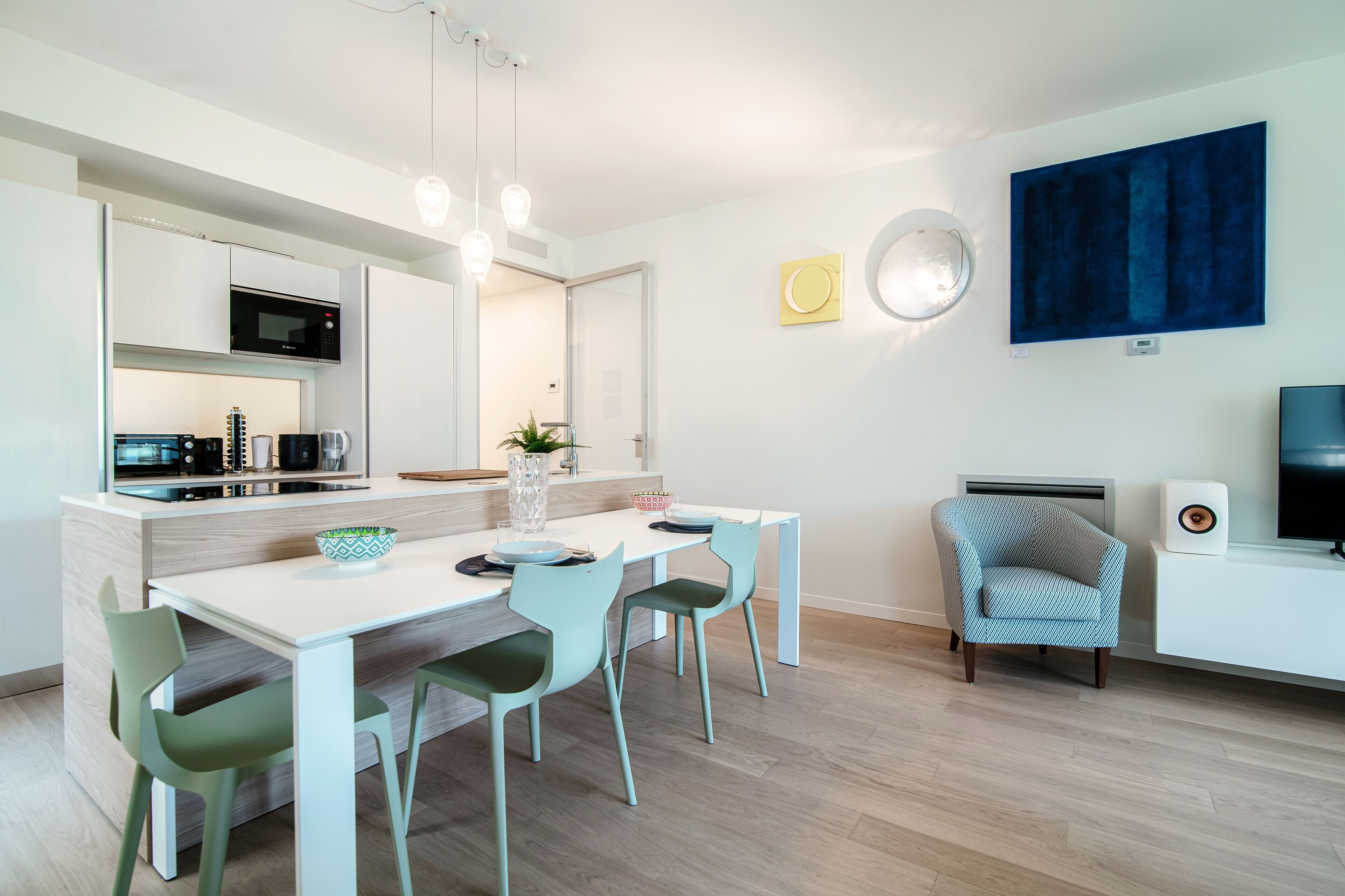 A modern kitchen with a dining area, a built-in microwave, and a seating arrangement with chairs.