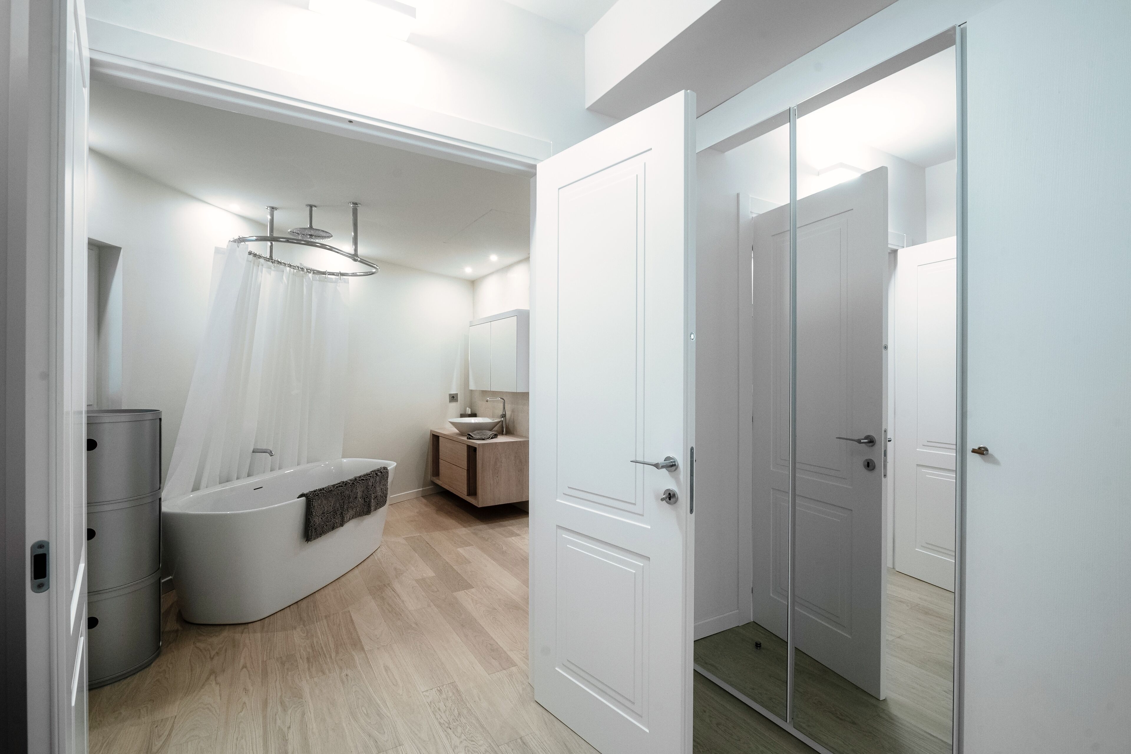 A modern bathroom with a freestanding bathtub, a vanity with a mirror, and a shower curtain.