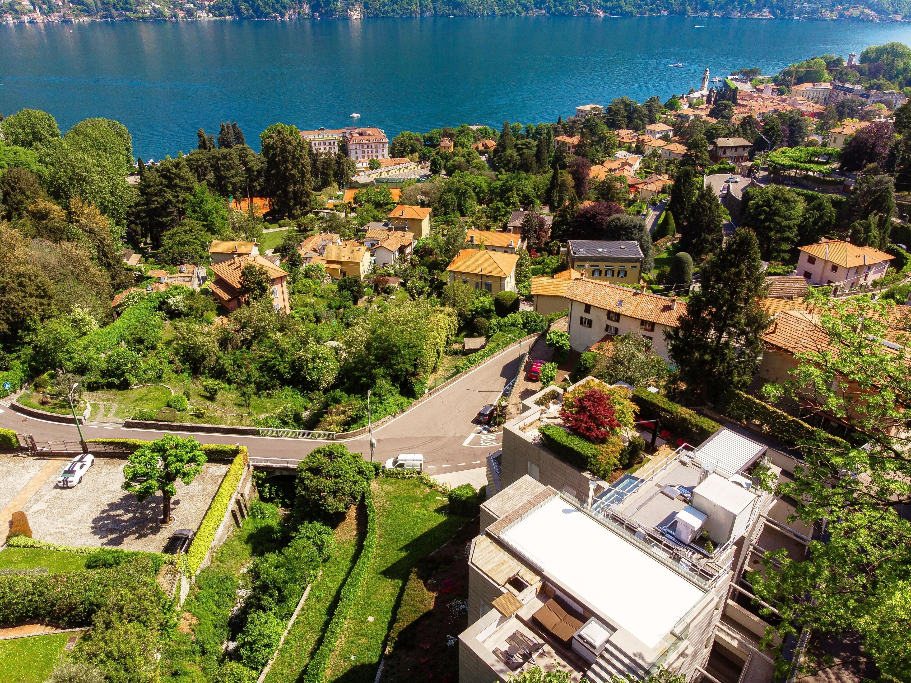 An aerial view of a lakeside town with residential buildings, a road, and a bridge.