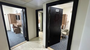 A hotel corridor with a tiled floor, a wooden desk with a television, and a door marked with the number 906. - Jawaher Al Hashmiya- 6 (Makkah)
