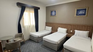 A hotel room with two single beds, a sofa, a chair, and a small table. - Jawaher Al Hashmiya- 6 (Makkah)