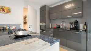 Una cocina moderna con estufa a gas, tabla de cortar y cafetera.