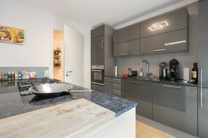 A modern kitchen with a gas stove, a cutting board, and a coffee machine. - Apartment 'Steni' with Mountain View, Private Terrace and Wi-Fi (Wehr)