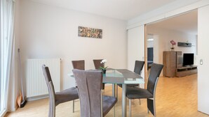 A modern dining area with a glass table, cushioned chairs, and a decorative wall piece.