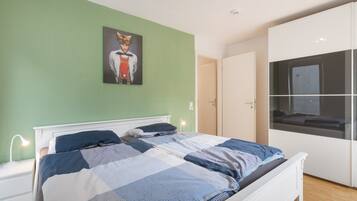 Ein Schlafzimmer mit einem Bett, einem Nachttisch, einer Nachttischlampe, einem Bild an der Wand und einem Kleiderschrank.