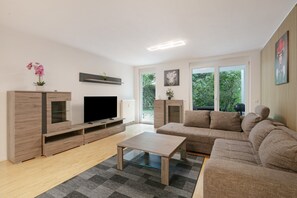 A modern living room with a flat-screen TV, wooden furniture, a sofa, and a coffee table. - Apartment 'Steni' with Mountain View, Private Terrace and Wi-Fi (Wehr)
