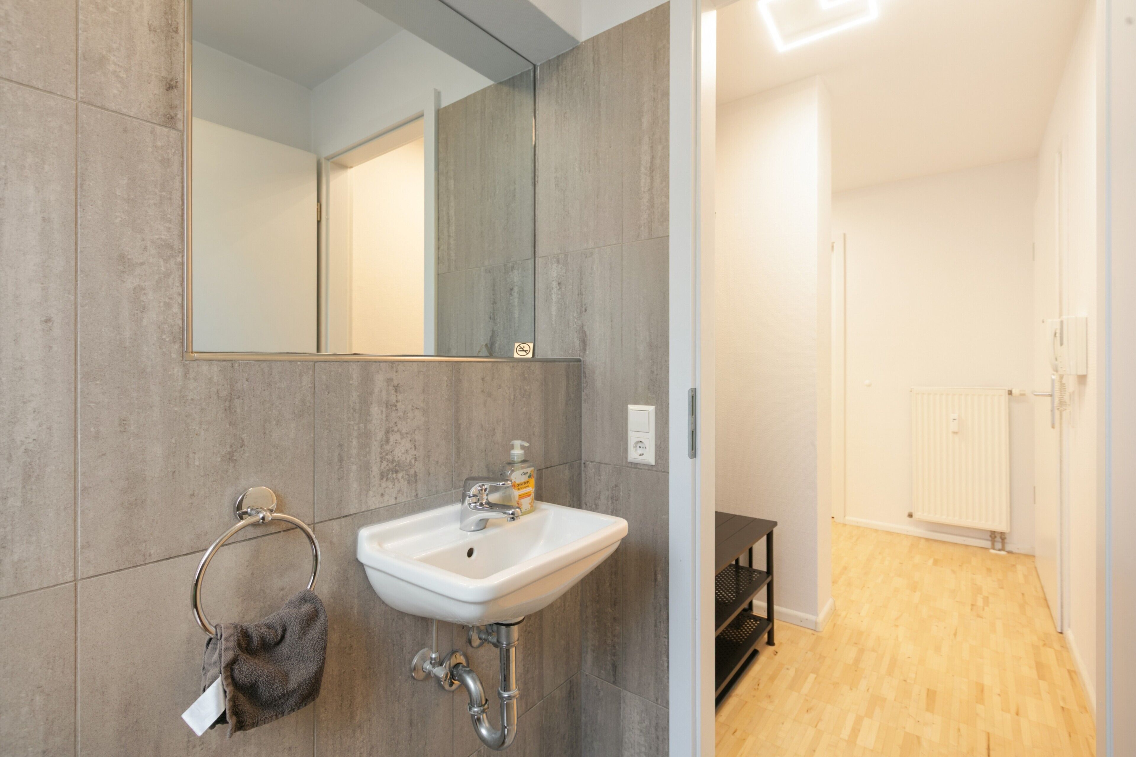 Un baño moderno con lavamanos blanco, toallero y espejo.
