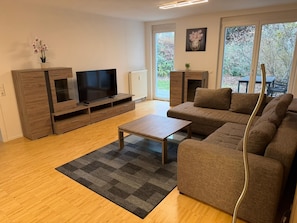 Ein modernes Wohnzimmer mit einer Couch, Fernseher, Holzschrank und Kamin.
