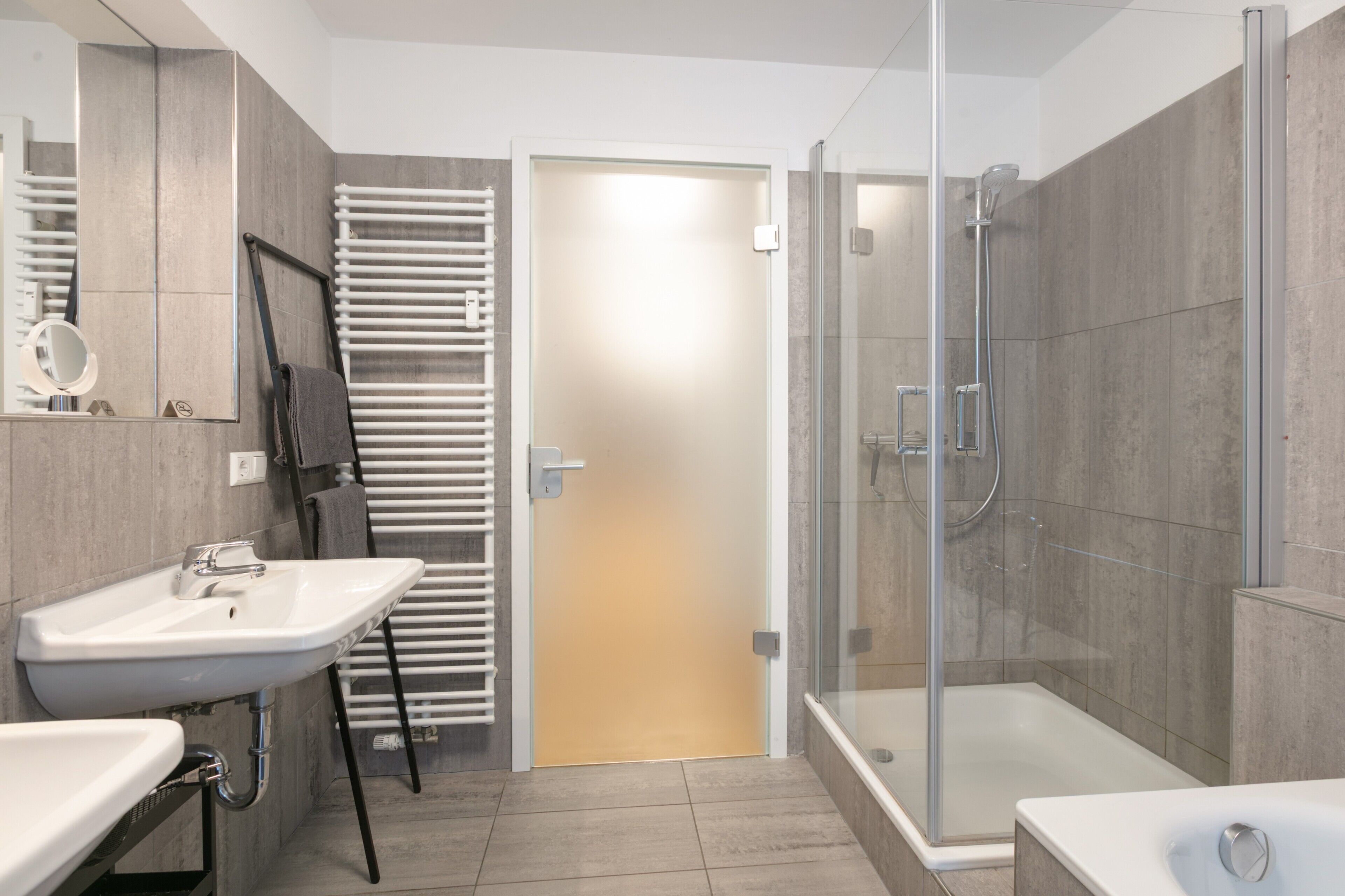 Ein modernes Badezimmer mit einer gläsernen Duschkabine, einer Badewanne und zwei Waschbecken.