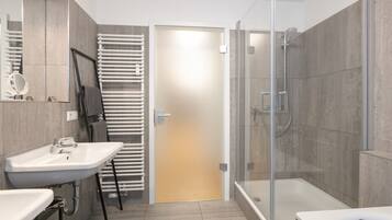 Ein modernes Badezimmer mit einer gläsernen Duschkabine, einer Badewanne und zwei Waschbecken.