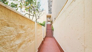 A narrow alleyway with a red-tiled floor, flanked by beige walls, leading to a staircase. - Double room - IMAR Hostel by Cadiz4Rentals (Cádiz)